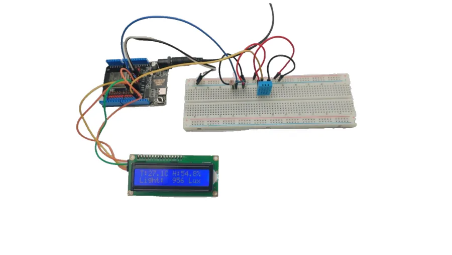 המערכת המורכבת במציאות: לוח ESP32 מחובר לברדבורד עם DHT11, ולמסך LCD1602 שמציג ״T:27.1C H:54.8%״ בשורה העליונה ו״Light: 956 Lux״ בתחתונה