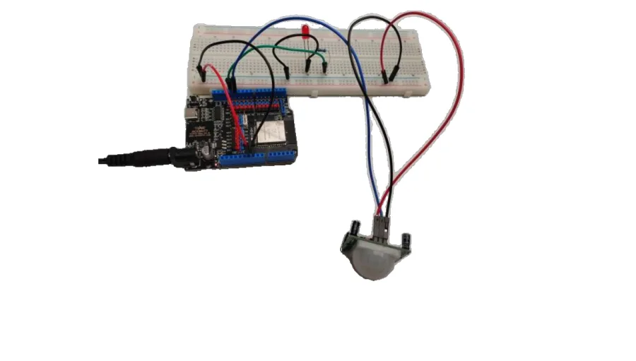 תצלום המערכת המורכבת — לוח ESP32, נורית על לוח ניסוי וחיישן PIR מחובר בשלושה חוטים
