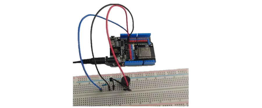 תצלום של המעגל הבנוי: לוח ESP32 מחובר בחוטים לזמזם פסיבי וטרנזיסטור על לוח הניסוי